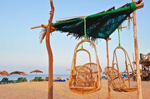 Exotic beach umbrellas and rocking chairs on tropical coast in Goa Exotic beach umbrellas and rocking chairs on tropical coast in Goa