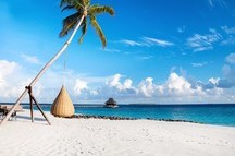 Beautiful tropical Maldives beach under cloudy sky with swings on coconut palm tree Beautiful tropical Maldives beach under cloudy sky with swings on coconut palm tree